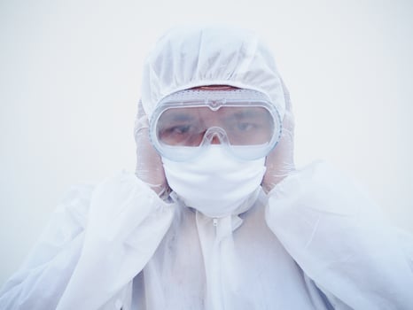 Asian doctor or scientist in PPE suite uniform covers ears with hands. Danger of coronavirus or COVID-19 concept isolated white background photo