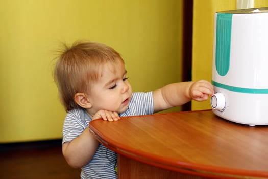 Little girl is trying to turn on a humidifier in bedroom. photo