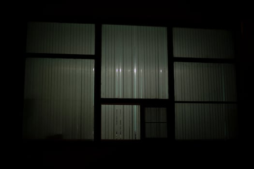Big window at night. Window in building. Blinds cover light of lamp. photo