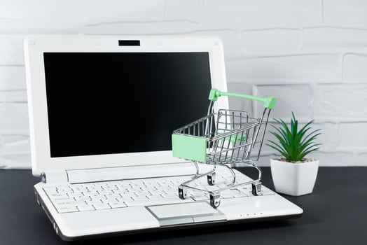 Online sale and Black Friday concept. Laptop and mini shopping cart on white background. photo