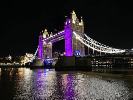 A view of Tower Bridge in London at night lit up in purple photo