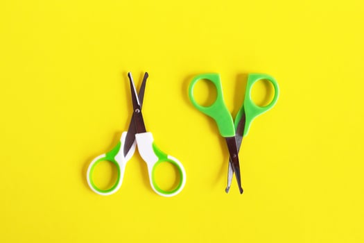 Two open baby green scissors on yellow background, flat lay with copy space. Baby care concept. photo