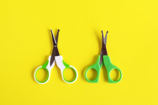 Two open baby green scissors on yellow background, flat lay with copy space. Baby care concept. photo