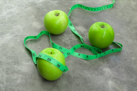Measure tape and green apple on stone background. photo