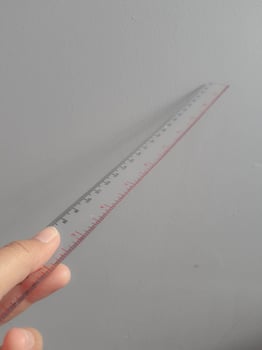 A hand is holding a plastic ruler. photo