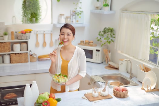 Beautiful Smiling Woman Eating Fresh Organic Vegetarian Salad In Modern Kitchen. photo