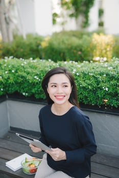 A young cute girl sitting in the park working scrolling a tablet photo