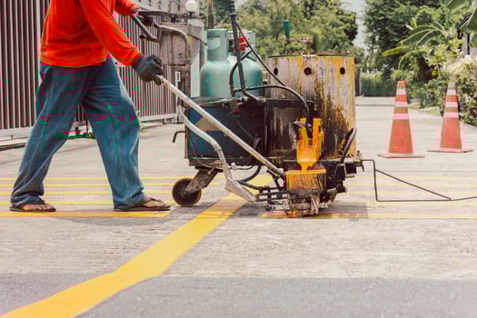 Road worker paint traffic lines on asphalt road surface. photo