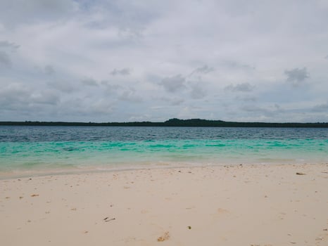 Beautiful sunny day on a calm pristine beach with grey skies in Indonesia photo