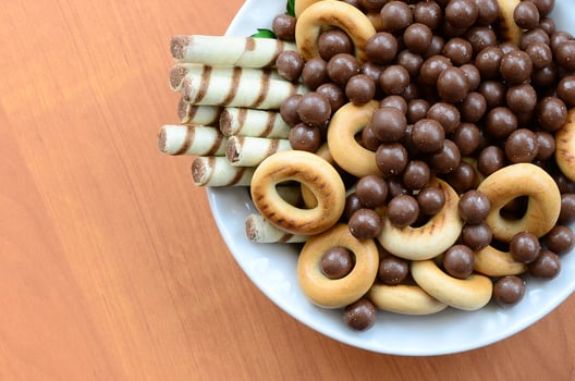 Crispy tubules, chocolate melting balls and bagels lie in a white plate on a wooden table. Mix of various sweets photo
