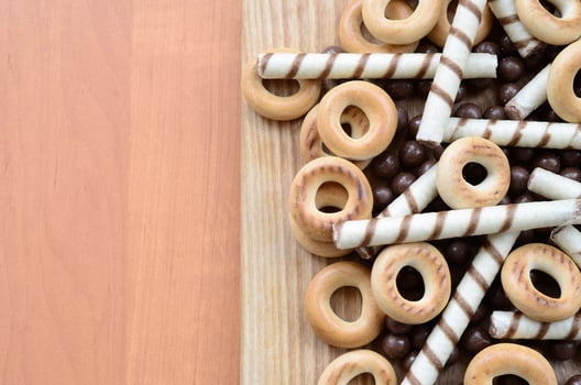 Crispy tubules, chocolate melting balls and bagels lie on a wooden surface. Mix of various sweets photo