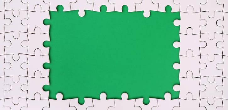 Framing in the form of a rectangle, made of a white jigsaw puzzle around the green space photo