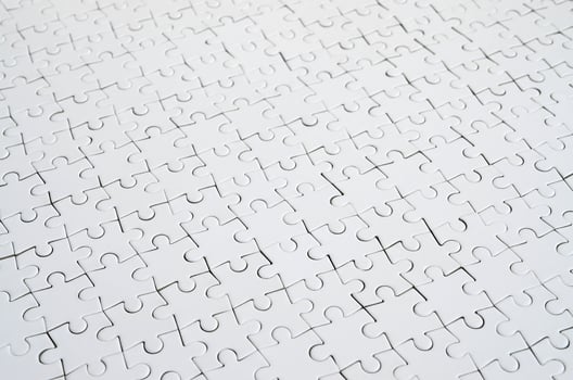 Close up of a white jigsaw puzzle in assembled state in perspective. Many components of a large whole mosaic are united photo