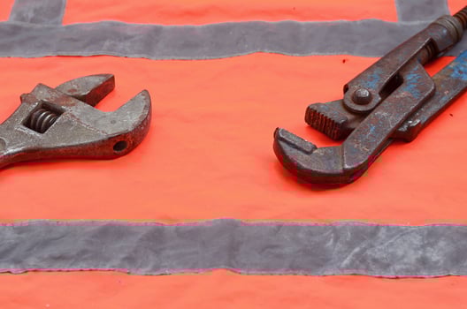 Adjustable and pipe wrenches against the background of an orange signal worker shirt photo