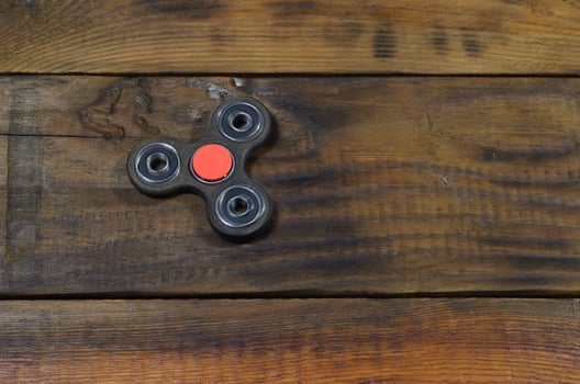 A rare handmade wooden fidget spinner lies on a brown wooden background surface. Trendy stress relieving toy photo