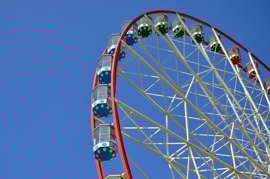 Big and modern multicolour ferris wheel on clean blue sky background photo