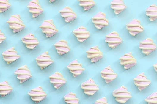 Colorful marshmallow laid out on blue paper background. pastel creative textured pattern. minimal photo