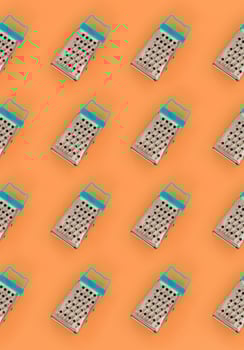Small stainless steel graters lies on a pastel colored paper. Kitchen accessories. Tools for cooking. Flat lay top view photo