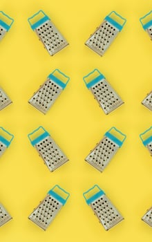 Small stainless steel graters lies on a pastel colored paper. Kitchen accessories. Tools for cooking. Flat lay top view photo