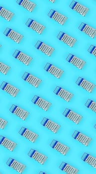 Small stainless steel graters lies on a pastel colored paper. Kitchen accessories. Tools for cooking. Flat lay top view photo