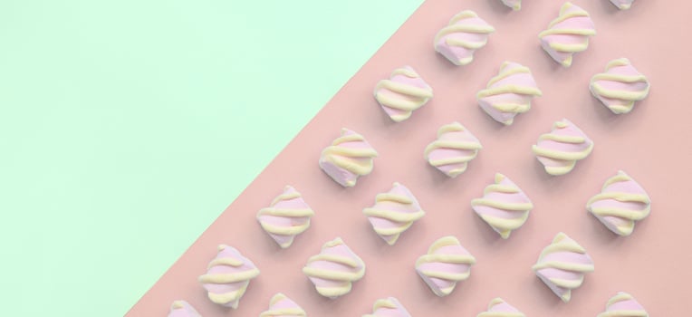 Colorful marshmallow laid out on turquoise and pink paper background photo