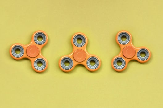 Many orange fidget spinners lies on texture background of fashion pastel orange color paper photo