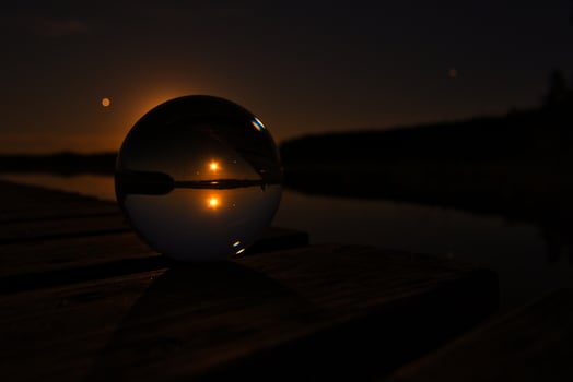Glass ball on a wooden pier at a Swedish lake at night. Stars and moon photo