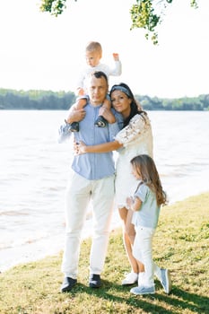 A happy family with two children have fun outdoors in summer by the lake photo