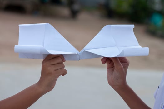 Hand of children holding paper airplane fold from reuse paper. It is a toy born of creativity and imagination. photo