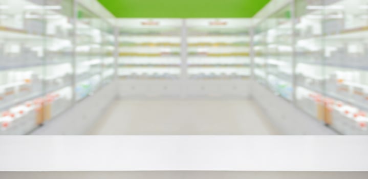 Empty white counter with pharmacy drugstore shelves blurred background photo