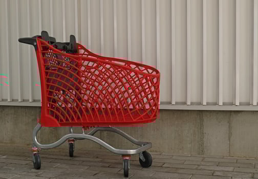 Empty red shopping on industrial wall background. Shop trolley at supermarket. Sale, discount, shopaholism, black friday, economy concept. Consumer society trend. Online Shopping Concept. photo