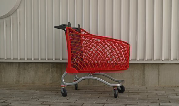 Empty red shopping on industrial wall background. Shop trolley at supermarket. Sale, discount, shopaholism, black friday, economy concept. Consumer society trend. Online Shopping Concept. photo