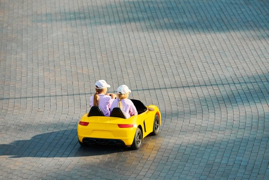 Two little girls driving toy car. Battery vehicle with remote control for children entertainment photo