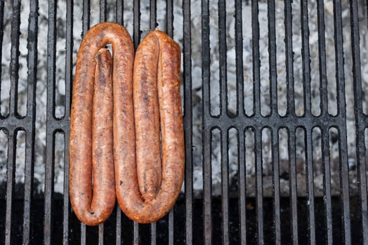 Top view shot of a sausage being grilled on a grill outdoors photo