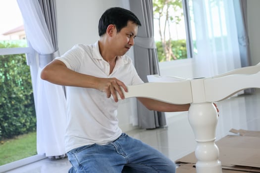 Asian man assembling white table furniture at home photo