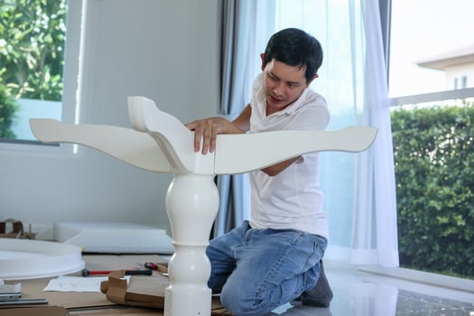 Asian man assembling white table furniture at home photo