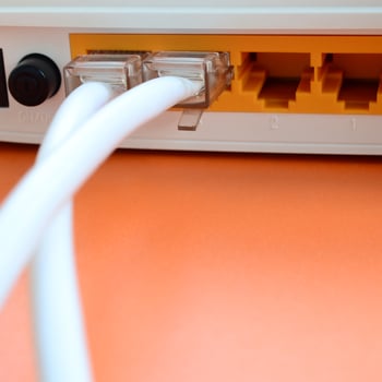 The Internet cable plugs are connected to the Internet router, which lies on a bright orange background. Items required for Internet connection photo