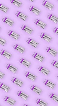 Small stainless steel graters lies on a pastel colored paper. Kitchen accessories. Tools for cooking. Flat lay top view photo