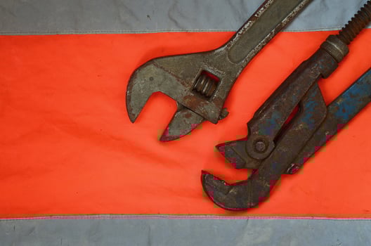 Adjustable and pipe wrenches against the background of an orange signal worker shirt photo