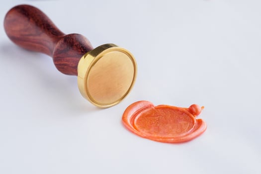 metal head stamp tool with wooden handle and wax seal on white paper photo