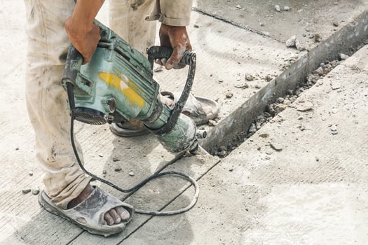 Construction worker using jackhammer drilling concrete surface photo