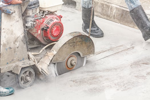 Worker using diamond saw blade machine cutting concrete road at construction site photo