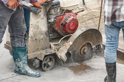 Worker using diamond saw blade machine cutting concrete road at construction site photo