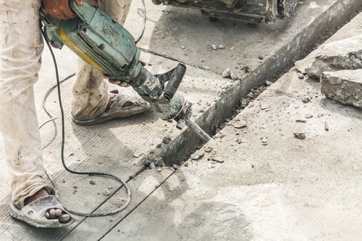 Construction worker using jackhammer drilling concrete surface photo
