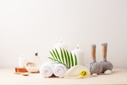 Spa treatment with herbal bags and candle on white background. Close up, copy space photo