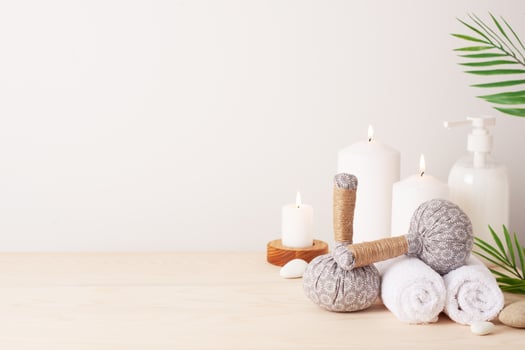 Spa treatment with herbal bags and candle on white background. Close up, copy space photo