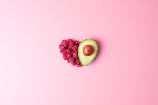 Creative summer concept. Heart shape made from fresh berries and avocado on pink background. Flat lay, copy space. photo
