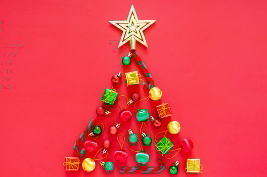Christmas tree made of New year ornament decorations on red background. Flat lay minimal Holiday concept. photo