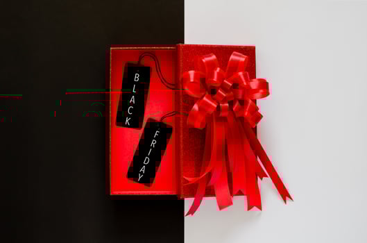 Red christmas box with red bow ribbon and black price tag on black and white background. Black Friday concept. photo