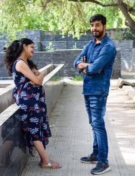 Indian couple posing for maternity baby shoot. The couple is posing in a lawn with green grass and the woman is falunting her baby bump in Lodhi Garden in New Delhi, India photo